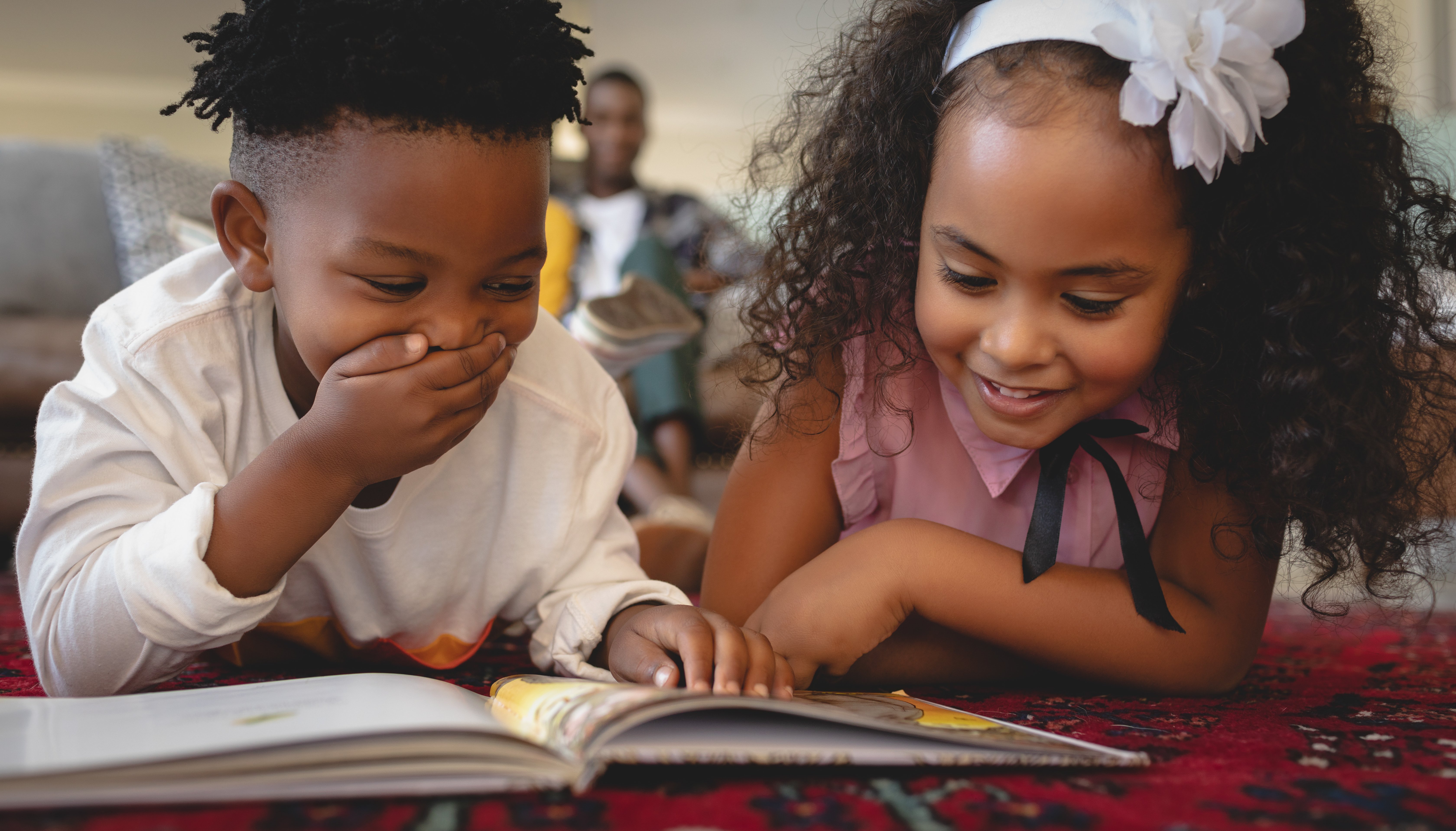 boy and girl reading book together and laughing and smiling